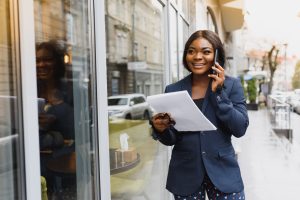 A pretty African american business woman talking on a cell phone at office building